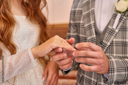 The groom puts a wedding ring on the bride's finger. Wedding ceremony. Wedding celebration.