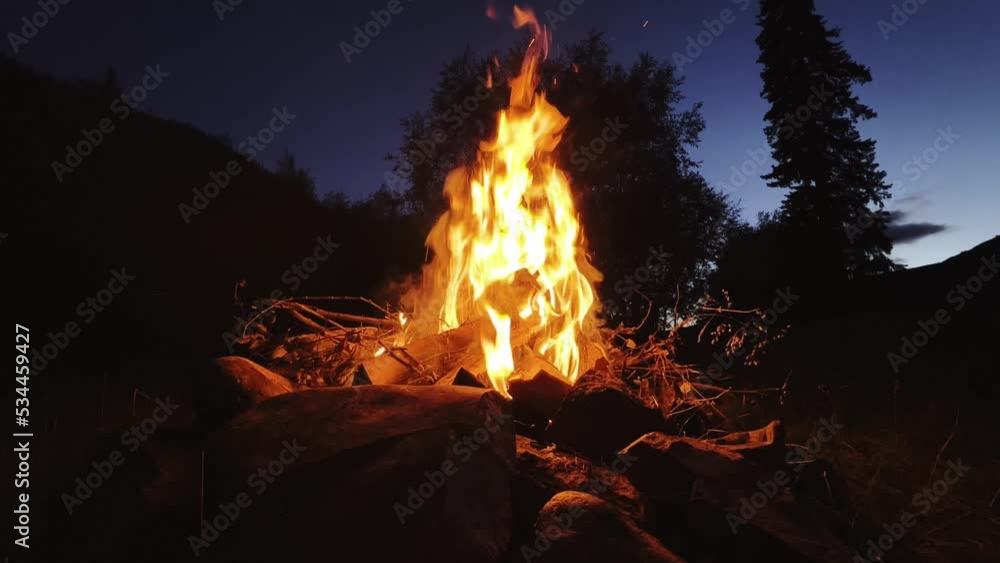 A bonfire burning in a tourist camp in the mountains. A beautiful bonfire burning wood on a summer evening. The concept of an active lifestyle, travel, hiking and camping. Slow motion video. A bonfire burning in a tourist camp in the mountains. A beautiful bonfire burning wood on a summer evening. The concept of an active lifestyle, travel, hiking and camping. Slow motion video.