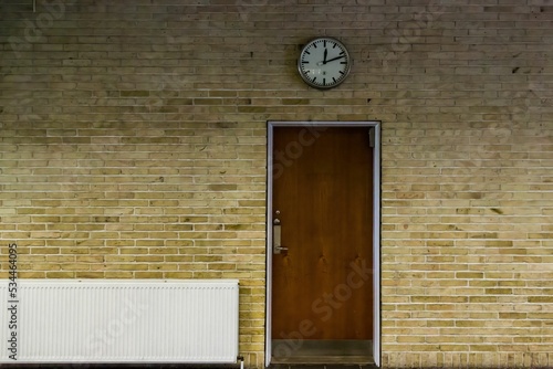 Old stone wall with a wooden door and a clock