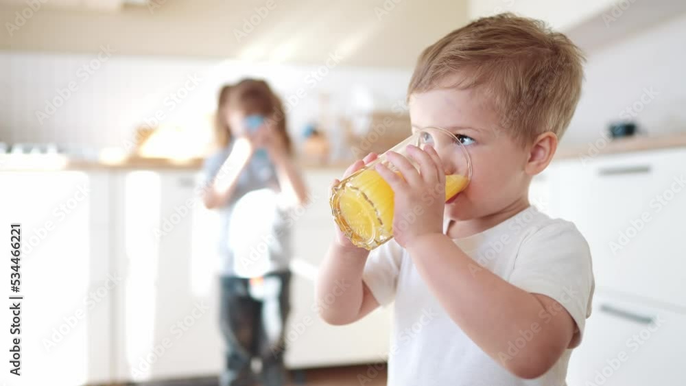 children drink juice. little boy in the kitchen drinking yellow juice from a glass cup. happy family kid dream concept. children drink juice in the kitchen. healthy eating concept fun children drink juice. little boy in the kitchen drinking yellow juice from a glass cup. happy family kid dream concept. children drink juice in the kitchen. healthy eating concept fun