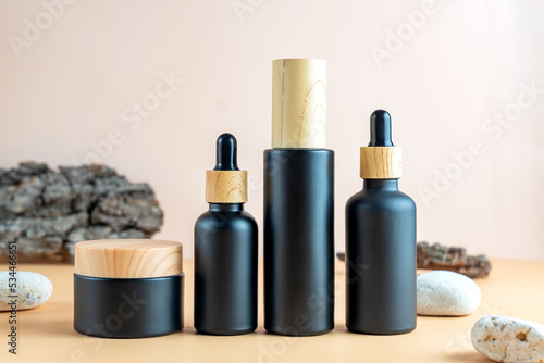 Serum, facial cleanser and moisturizer cream on beige background with bark tree and stones. Beauty products mockup. Healthcare skincare concept
