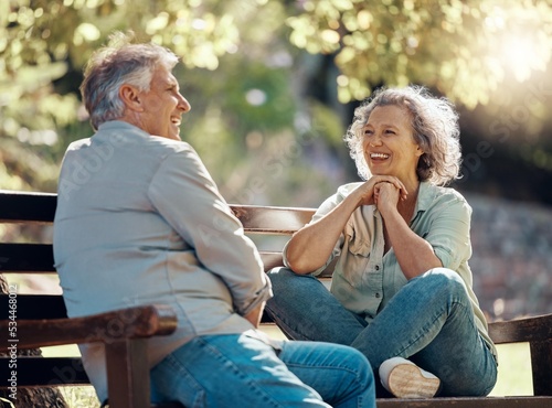 Park bench, couple and senior people with love and happiness in nature enjoying summer. Happy smile of elderly woman and man retirement together relax laughing outdoor having a fun conversation
