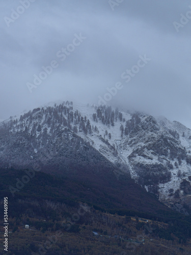 The snow-capped and cloud-covered peaks of the Val di Mello, during a spring day, near the town of San Martino, Italy - May 2022.