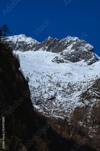 the mountains of val masino and val di mello with fresh snow, during a sunny day, near the town of San Martino, Italy - April 2022.