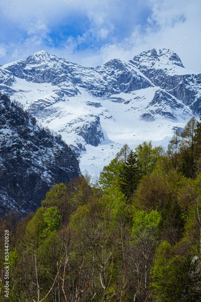 the mountains of val masino and val di mello with fresh snow, during a sunny day, near the town of San Martino, Italy - April 2022.