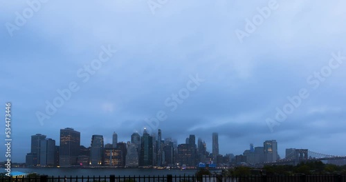 Overcast Sky Fading Into Night In Time-Lapse With New York City's September 11th Memorial Lights Appearing Through Clouds photo
