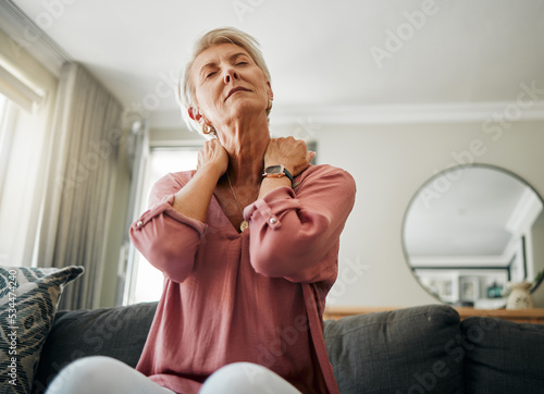 Senior woman, neck pain and stress in living room home of spine injury, fibromyalgia and osteoporosis. Sick, tired and fatigue lady in orthopedic, arthritis and health problem stretching body muscle photo