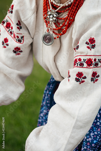 Elements of Ukrainian traditional national costume closeup: embroidered shirt, vyshyvanka, skirt, necklace. Culture of Ukraine