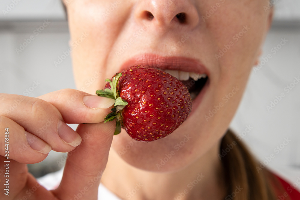 Young woman enjoying eating strawberry on a light background, closeup Young woman enjoying eating strawberry on a light background, closeup