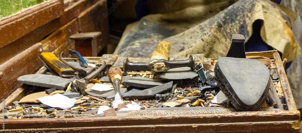 Traditional cobbler's table with tools for shoe repair, hammer, cobbler's pliers, polisher, repair leftovers, shoe, etc...