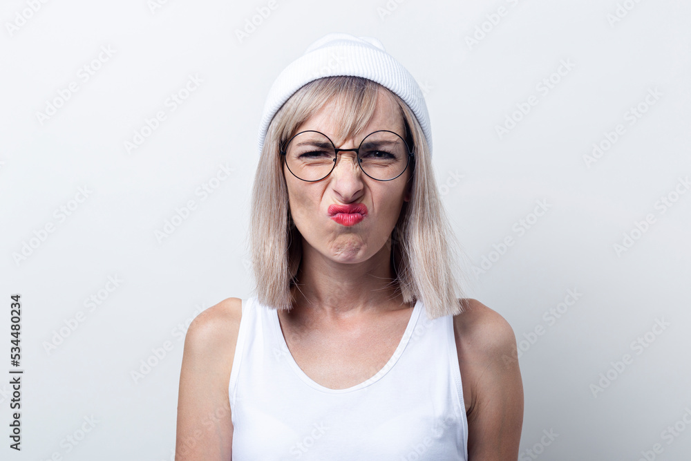 Blond young woman twisted with glasses, a white hat on a light background Blond young woman twisted with glasses, a white hat on a light background