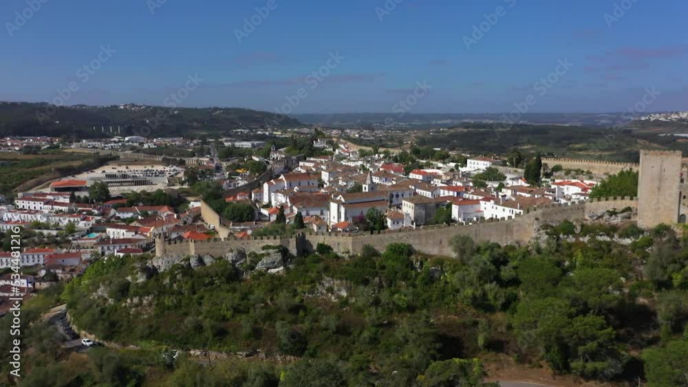 Aerial view around the city walls, towards the Igreja de Santa Maria church in sunny Obidos, Portugal - circling, drone shot Aerial view around the city walls, towards the Igreja de Santa Maria church in sunny Obidos, Portugal - circling, drone shot