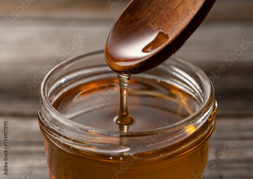 Canvastavla Honey and wooden spoon in glass container on old wooden background