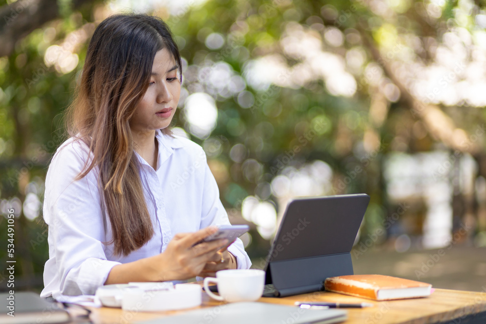 Outdoor business woman wearing casual clothes is working on a laptop and modern equipment in a natural and comfortable setting. Outdoor business woman wearing casual clothes is working on a laptop and modern equipment in a natural and comfortable setting.