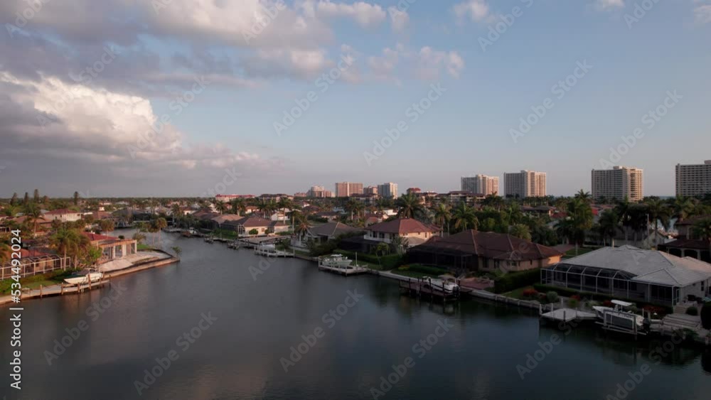 Aerial over Marco Island Flordia beach town at sunset. Resort Hotels on the beach in the distance. Houses and boats on the canal. Aerial over Marco Island Flordia beach town at sunset. Resort Hotels on the beach in the distance. Houses and boats on the canal.