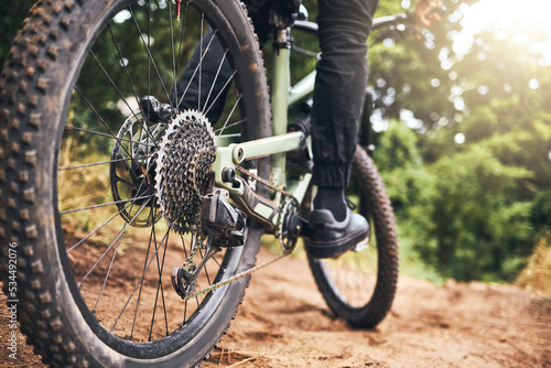 Bicycle, forest and wheels on a dirt road trail for fitness, adventure workout and exercise. Closeup of a sports bike, outdoor sand track and tire with an athlete cycling in nature for fun and health
