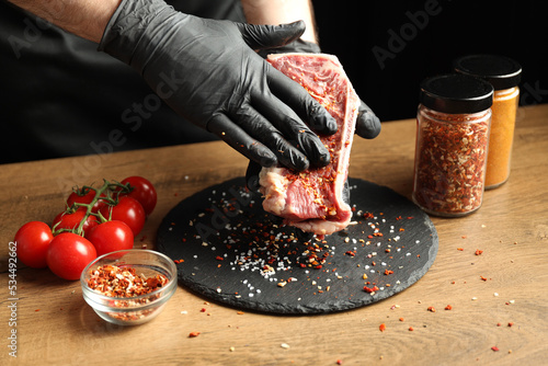 The chef rubs a beef steak with spices. photo