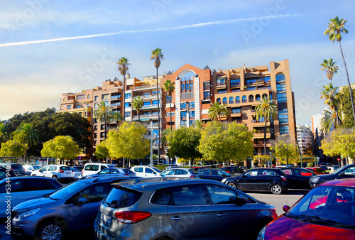 Сars in a parking lot in the city near office buildings and apartments. Parking with cars near the coastline with palm trees. Facade building with Palm trees. Architecture of modern buildings.