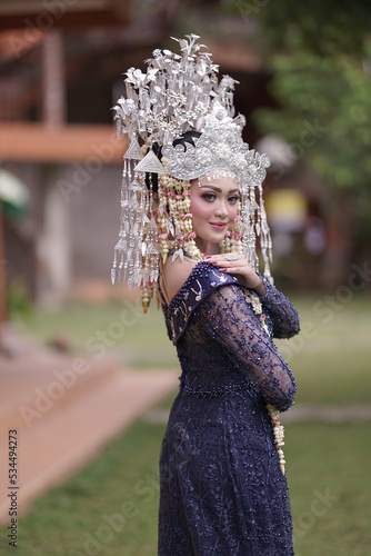 The model who is wearing suntiang traditional clothes from the city of padang, indonesia, looks very elegant and beautiful photo