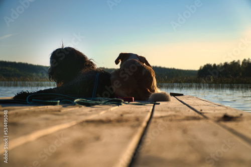 Dog lovers lying on a jetty and looking at the lake in Sweden. Goldendoodle and mix photo