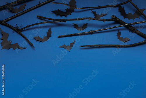 Black branches  paper bats and spiders on blue background  above view with space for text. Halloween celebration