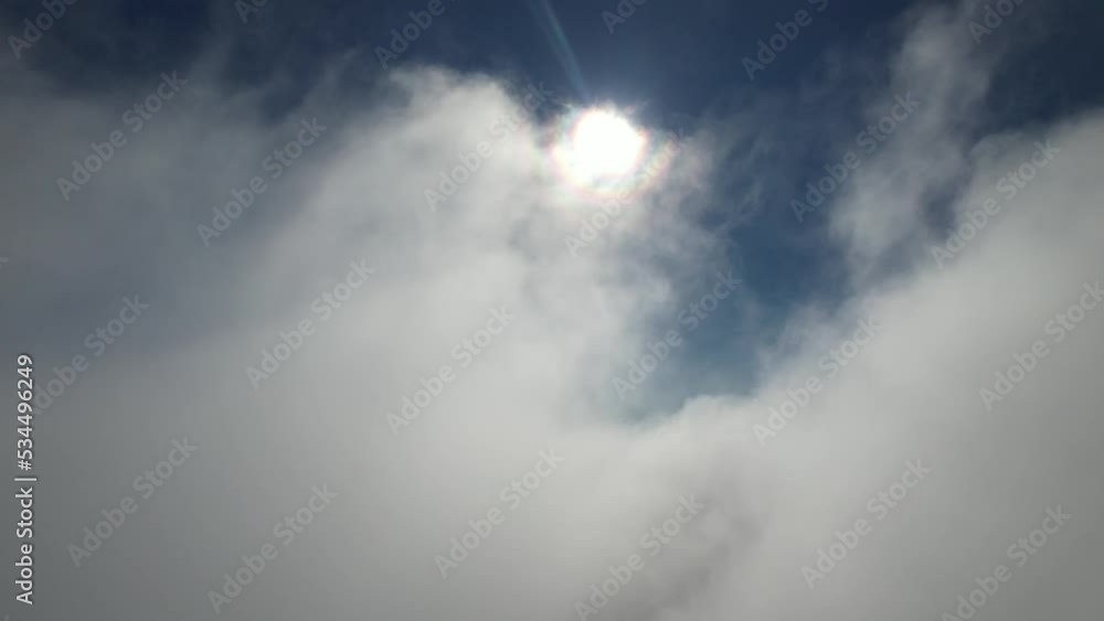 clouds float across the blue sky in front of the sun clouds float across the blue sky in front of the sun