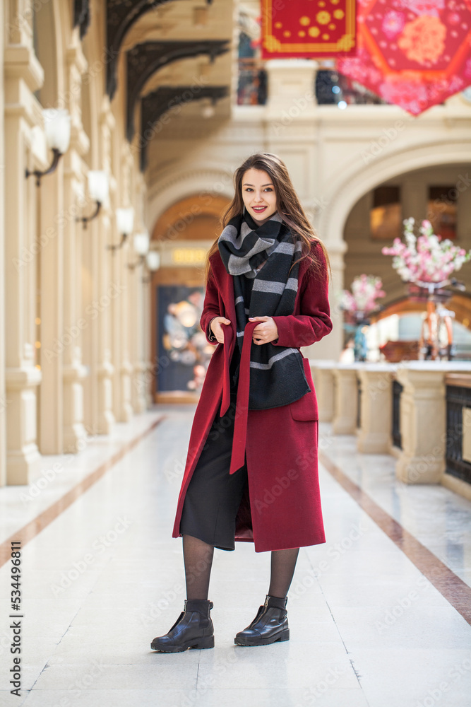 Portrait of a young brunette girl in a crimson red autumn coat