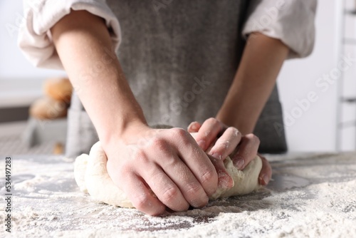 Woman kneading dough at table in kitchen, closeup © New Africa