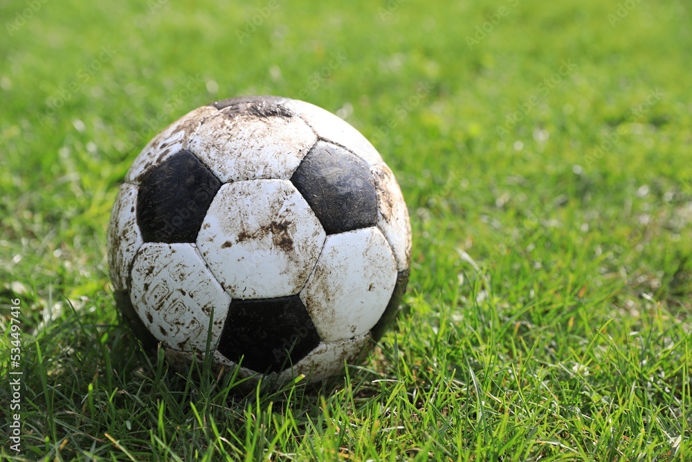 Obraz premium Dirty soccer ball on green grass outdoors, space for text
