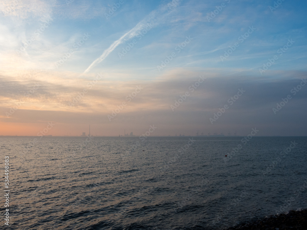 Blick vom Friesenstrand in Tossens über den Jadebusen auf die Industrieanlagen in Wilhelmshafen bei Sonnenuntergang Blick vom Friesenstrand in Tossens über den Jadebusen auf die Industrieanlagen in Wilhelmshafen bei Sonnenuntergang
