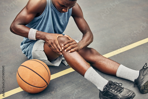 Fitness, basketball knee injury or pain while on basketball court holding leg in exercise, training or sport workout. Professional athlete, health or sports man with accident in street game or event photo