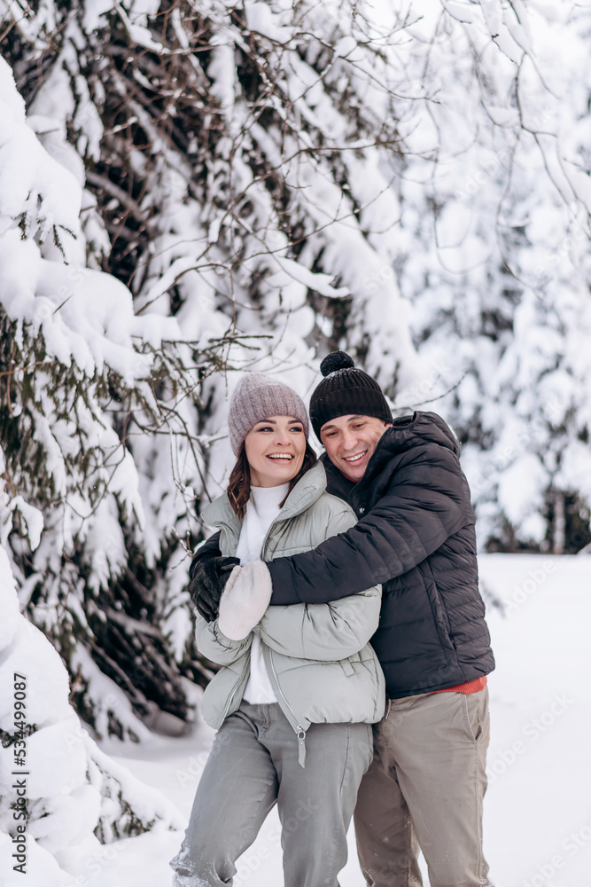 Young couple in love hugging in the winter forest and having fun spending time together.Winter,Valentine's day,newlyweds, tenderness and love. Young couple in love hugging in the winter forest and having fun spending time together.Winter,Valentine's day,newlyweds, tenderness and love.