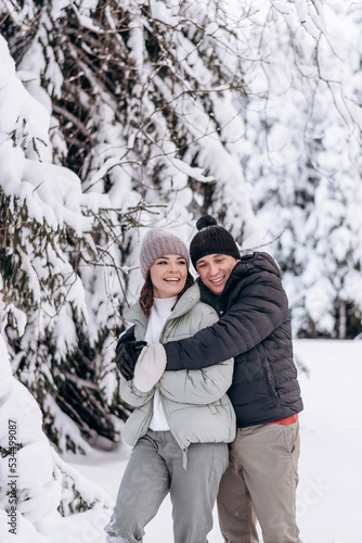 Young couple in love hugging in the winter forest and having fun spending time together.Winter,Valentine's day,newlyweds, tenderness and love.