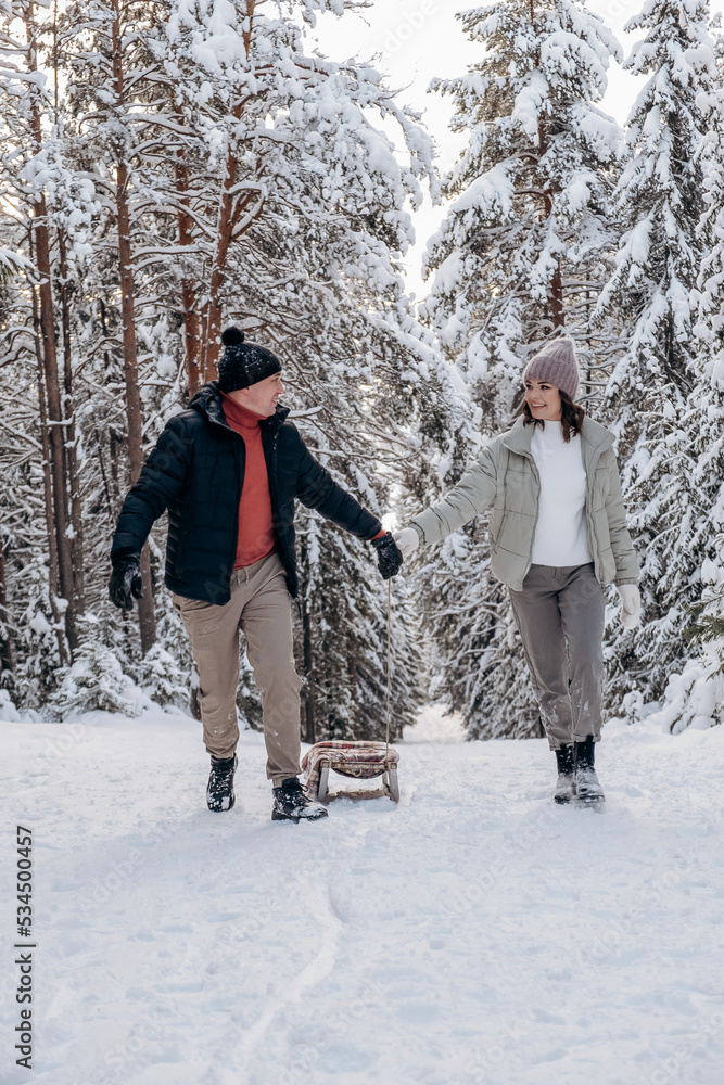 Young couple in love is sledding in a winter forest and having fun spending time together.Winter,active lifestyle,Valentine's day,newlyweds,tenderness and love.Selective focus.