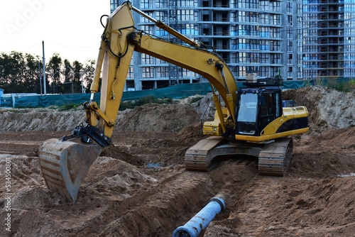 Sewage drainage system mounting at construction site. Excavator during laying sewer pipe and main systems. Civil infrastructure, water lines, sanitary sewers and storm sewers. Laying sewer pipes.