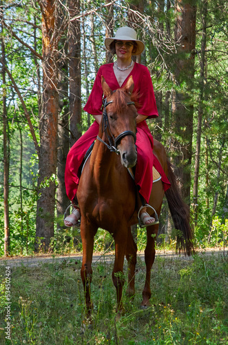 Woman in red dress rides a horse in early spring © Max