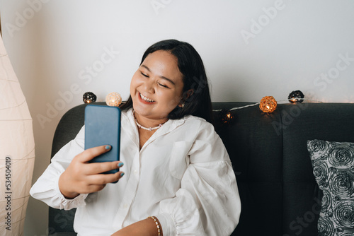 Young Asian woman using smartphone at home photo
