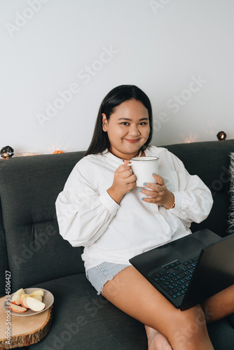 Portrait of a freelancer sitting on the couch and using laptop at home