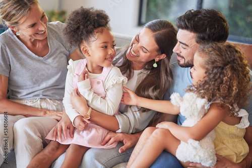 Love, relax and happy family introduction on sofa, laughing and playing in a living room together. Parents, kids and grandmother talking and enjoying quality time with sweet interracial children