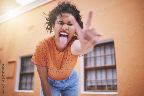 Photography Closeup beautiful mixed race fashion woman pouting and gesturing peace against an orange wall background in the city