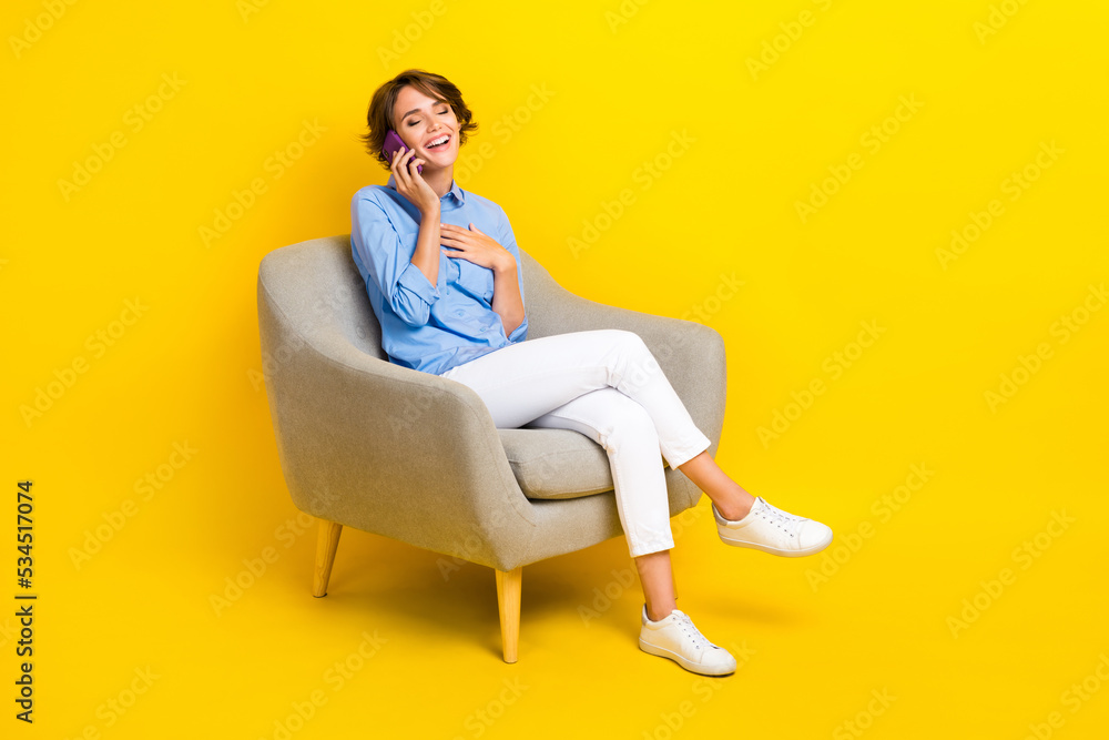 Full length photo of funky pretty girl dressed blue shirt communicating modern gadget empty space isolated yellow color background Full length photo of funky pretty girl dressed blue shirt communicating modern gadget empty space isolated yellow color background