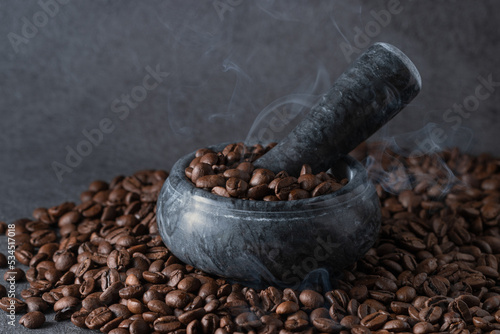 coffee beans and smoke in a marble mortar on a dark background, roasted coffee