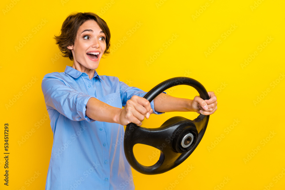 Photo of impressed funny girl dressed blue shirt riding auto looking empty space isolated yellow color background Photo of impressed funny girl dressed blue shirt riding auto looking empty space isolated yellow color background