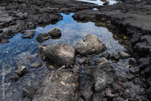 black lava rock and stones above and below coastal sea water