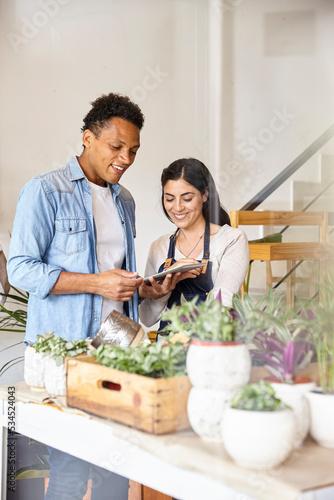 Small business plant shop coworkers looking at digital tablet