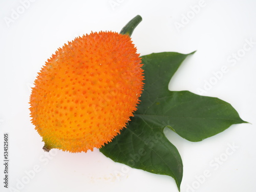 Orange Gac fruit and leaves on white background. Closeup photo, blurred.
