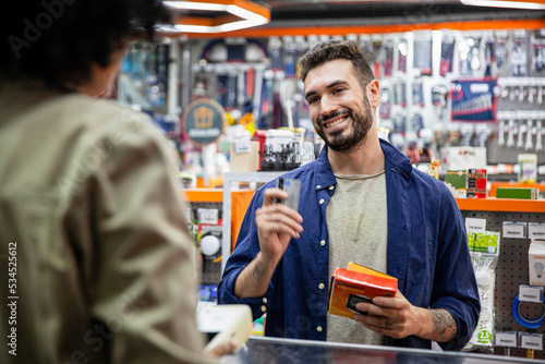Male customer paying with credit card to African American hardware shop worker
