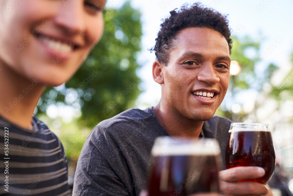 Portrait of happy young African-American man smiling at camera while holding a glass of beer Portrait of happy young African-American man smiling at camera while holding a glass of beer