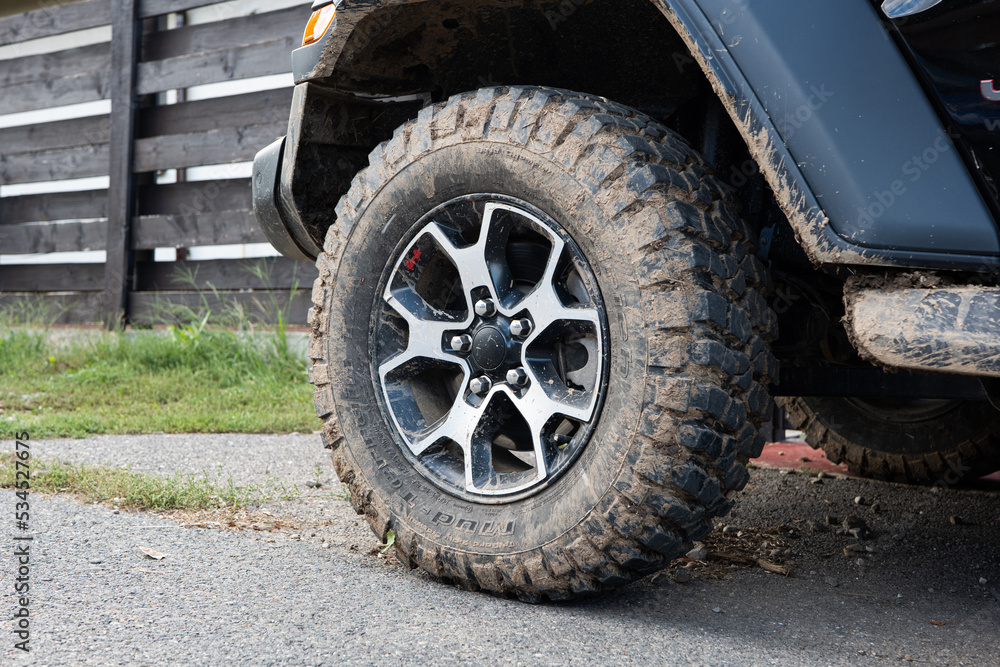 Dried mud on SUV's off-road mud tires. Close up low angle view, no people