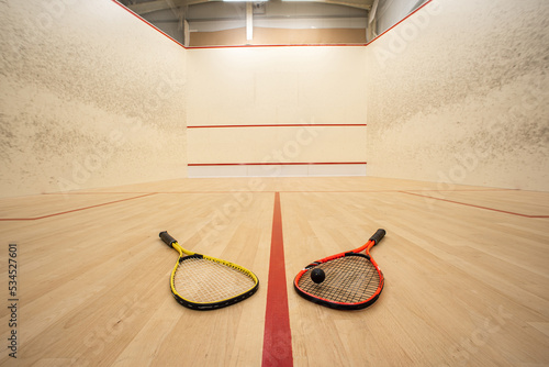 Empty squash court ultra-wide angle view. Racket and ball on the ground, no people